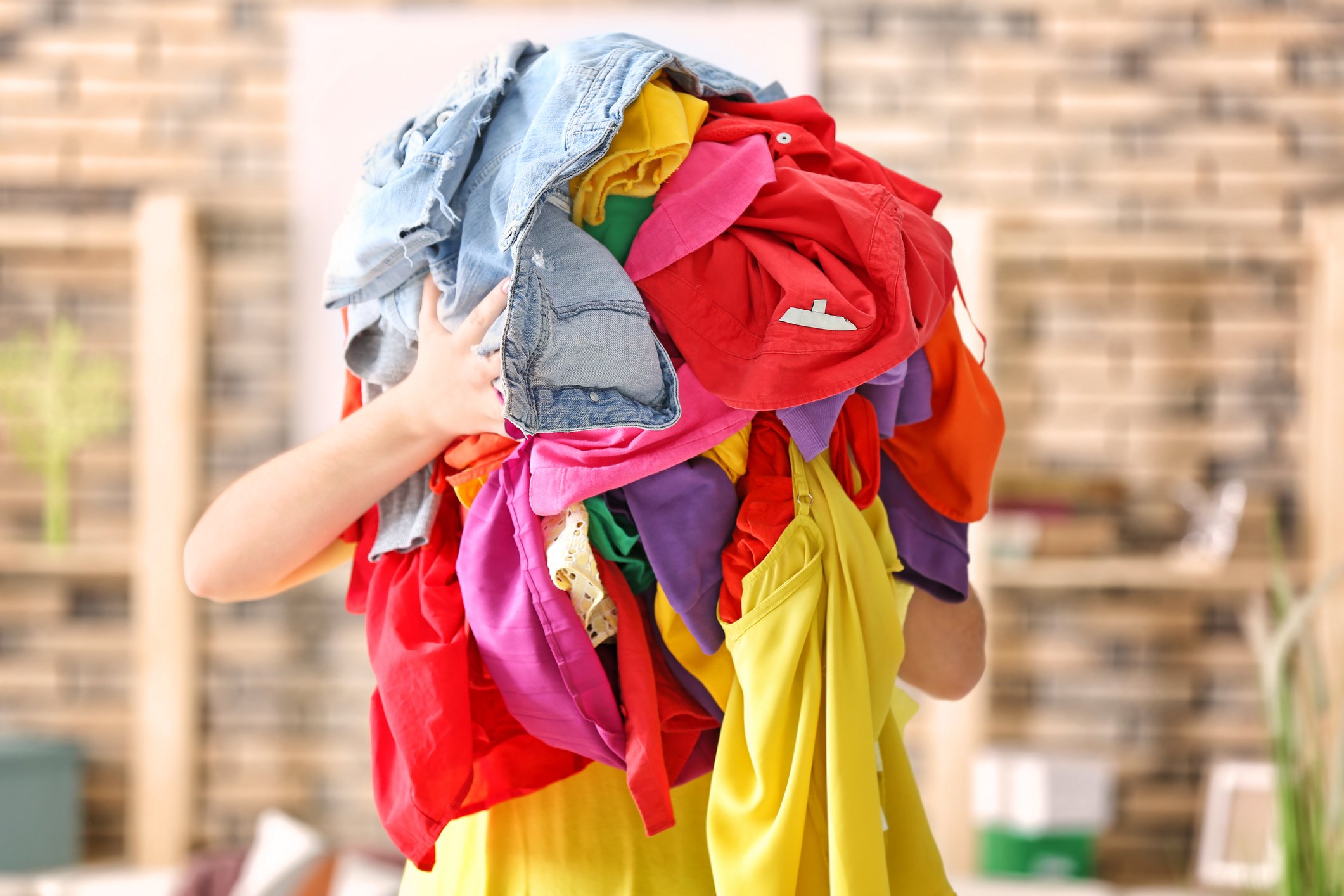 Woman-holding-pile-of-colourful-clothes