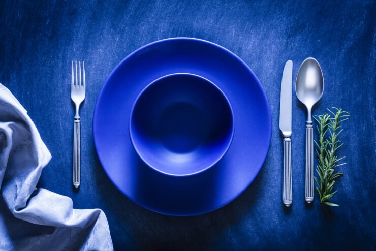 consumer-pr-photo-of-a-blue-plate-and-bowl-with-a-spoon-fork-and-knife-at-each-side-on-a-textured-blue-background