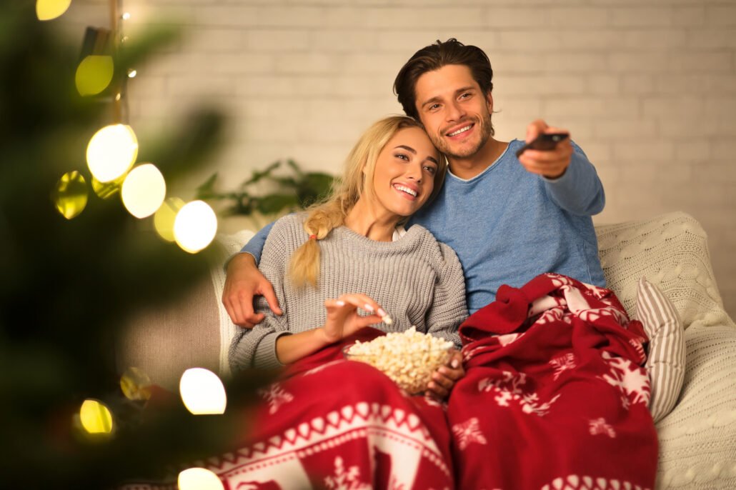 Loving-couple-watching-tv-at-Christmas-eve-and-eating-popcorn-at-home