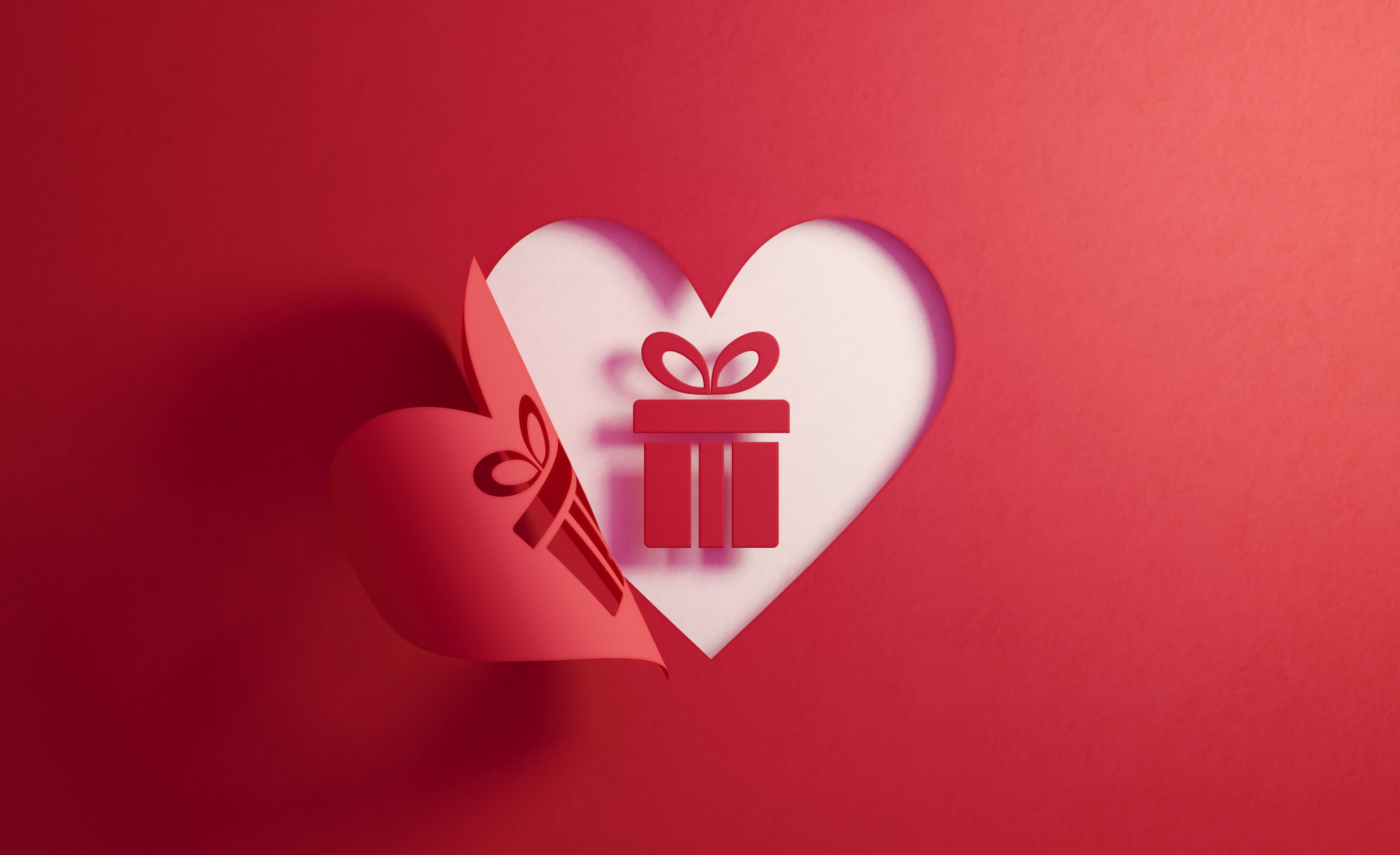 Gift-box-icon-inside-of-a-red-folding-heart-shape-on-white-background