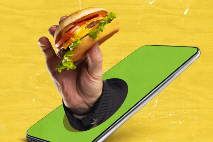 food-pr-shot-of-hand-holding-a-burger-coming-out-of-a-smartphone