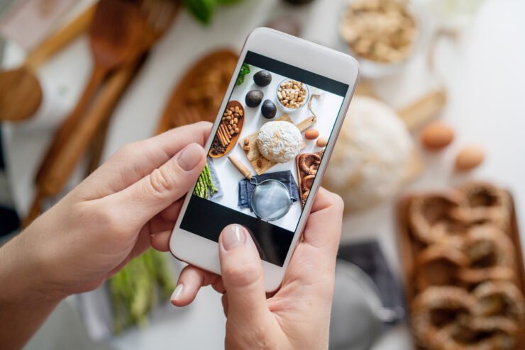 food-and-drink-brands-influencer-holding-phone-to-take-picture-of-food-display