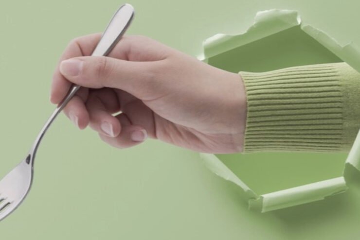 female-hand-holding-a-fork-and-coming-out-of-a-hole-in-paper