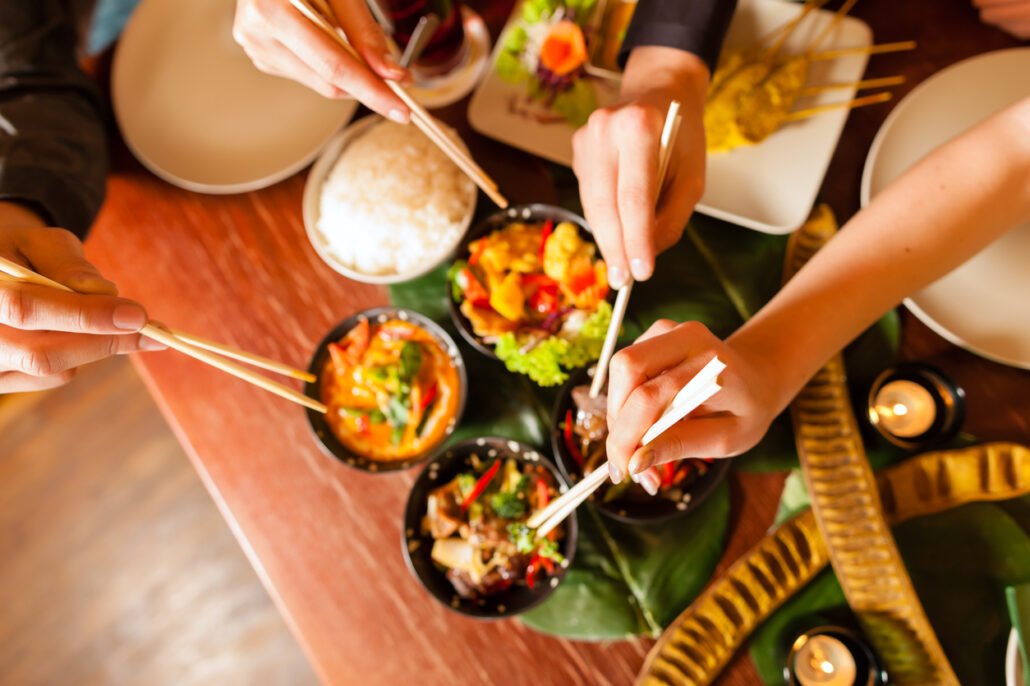 People-eating-a-Thai-takeaway-with-chopsticks-close-up-on-hands-and-food