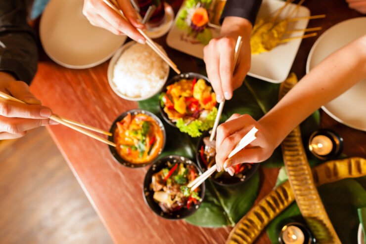 People-eating-a-Thai-takeaway-with-chopsticks-close-up-on-hands-and-food