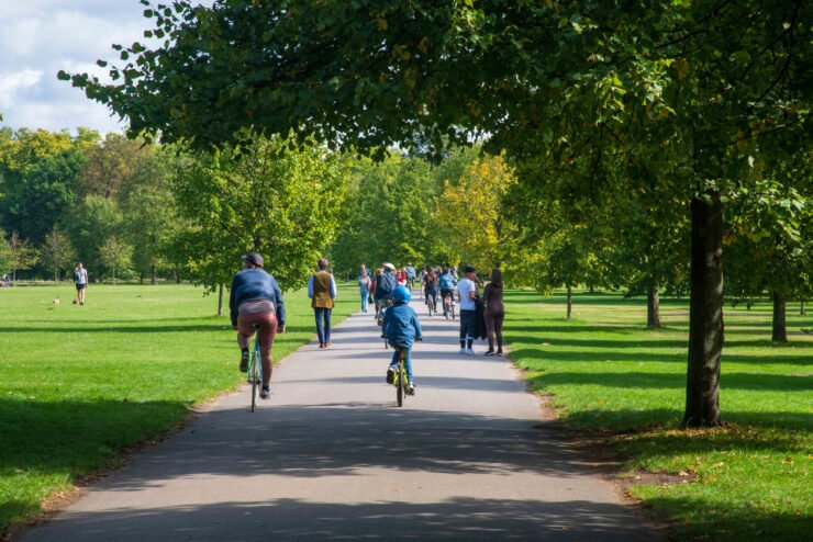 People-walking-and-cycling-on-a-path-in-a-green-park- with-trees