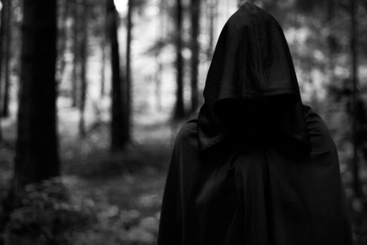 Man-in-black-cape-and-hood-in-forest