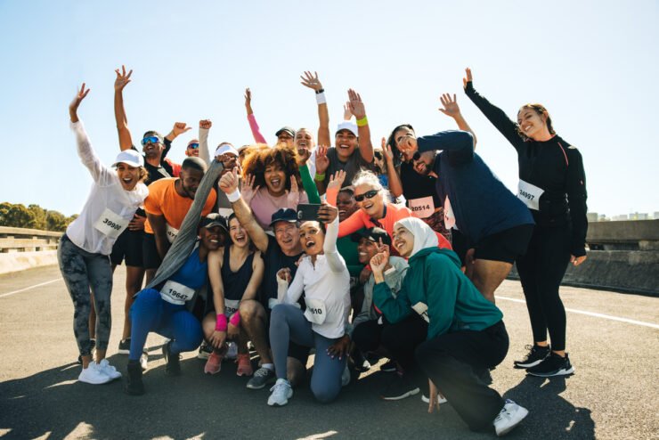 A-diverse-and-joyful-group-of-people-gathers-for-a-selfie-after-finishing-a-run-on-a-sunny-day-The-image-captures-the-spirit-and-energy-of-fitness-health-and-community-engagement