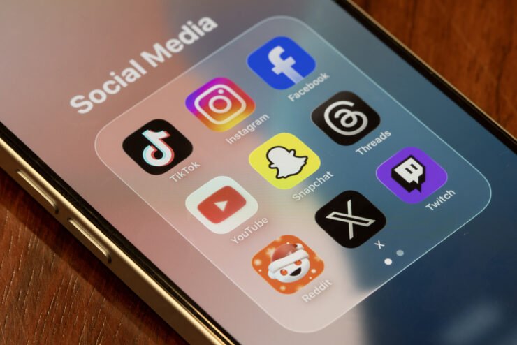 Assorted social media apps (TikTok, Instagram, Facebook, YouTube, Snapchat, Threads, Reddit, X, and Twitch) on iPhone screen